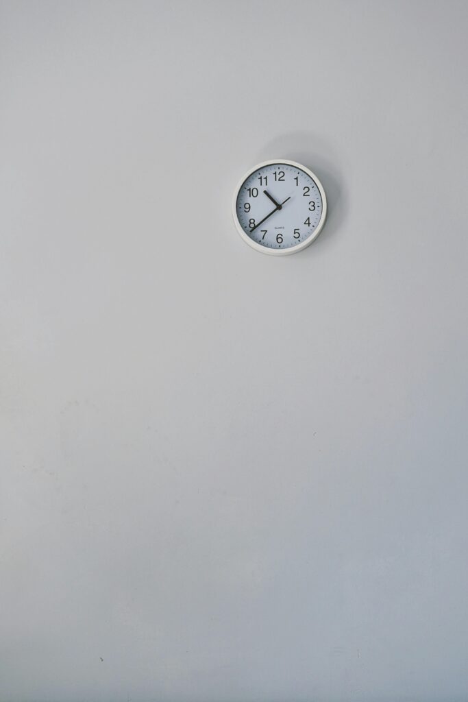 A minimalist white wall clock against a plain background, showcasing simple design.
